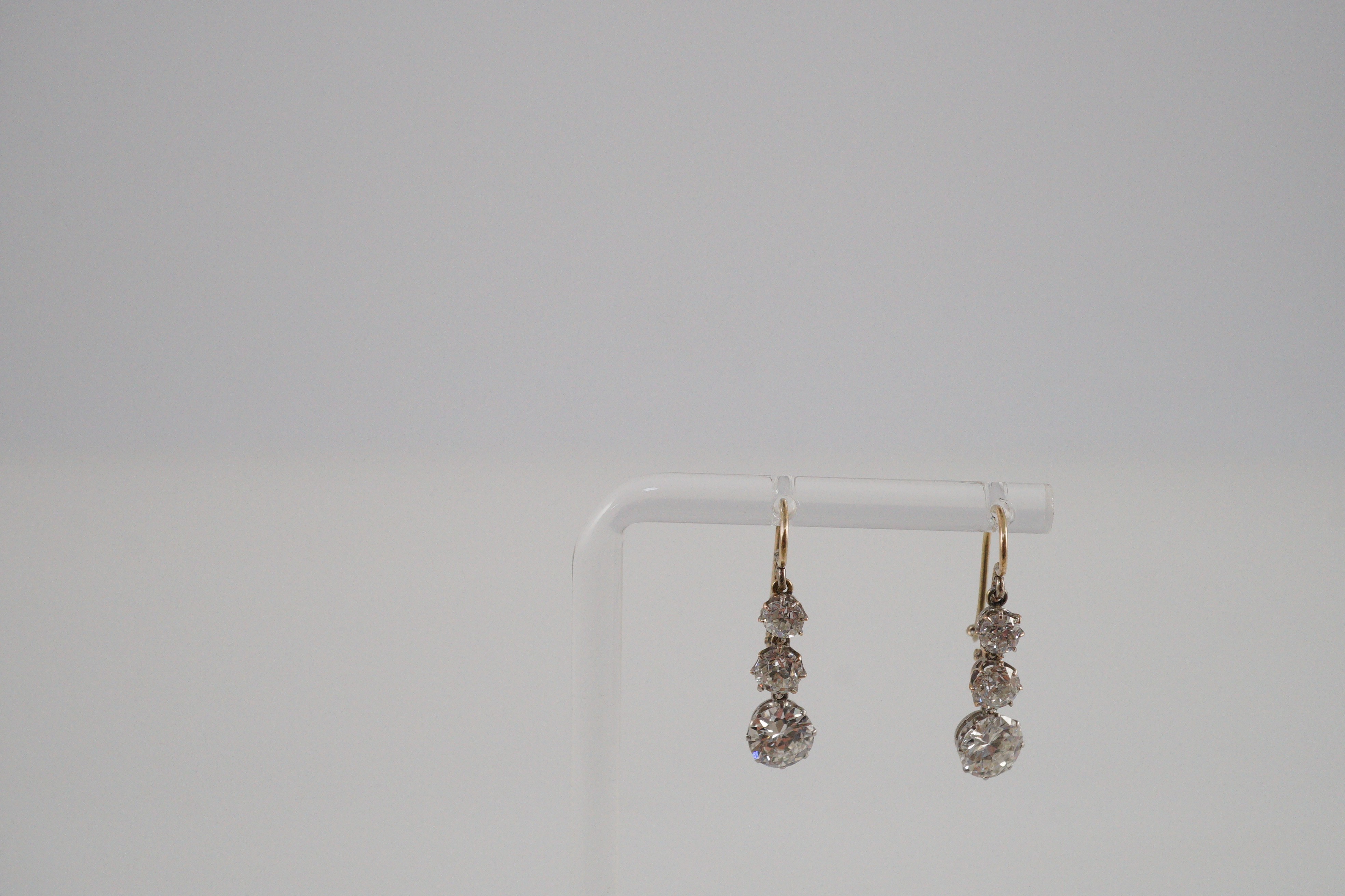 A pair of early to mid 20th century gold, platinum and graduated three stone diamond set drop earrings